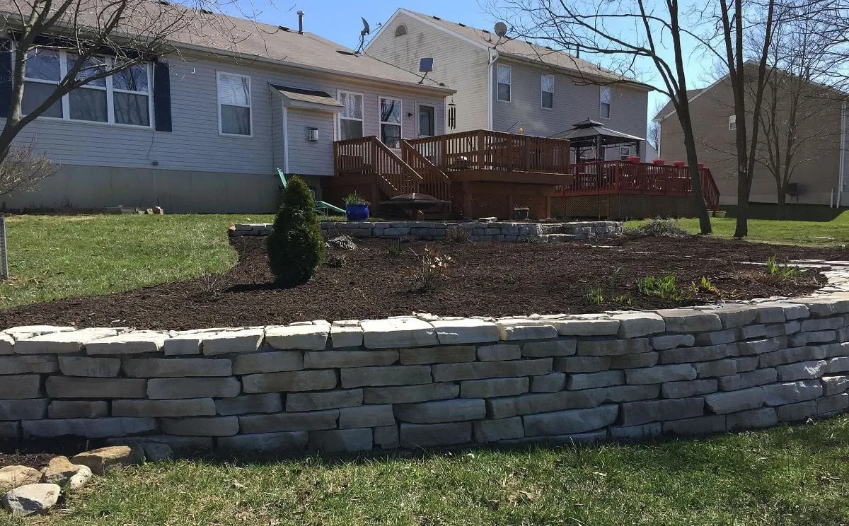 Block retaining wall holding a raised mulch bed in a backyard Block retaining wall holding a raised mulch bed in a backyard